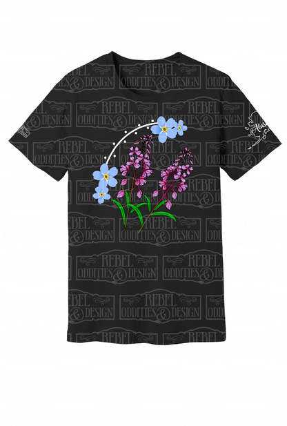 Black t-shirt with the shape of Alaska on the left sleeve, a small logo on the right sleeve, and a Forget-Me-Not and Fireweed design on the front against a white background.