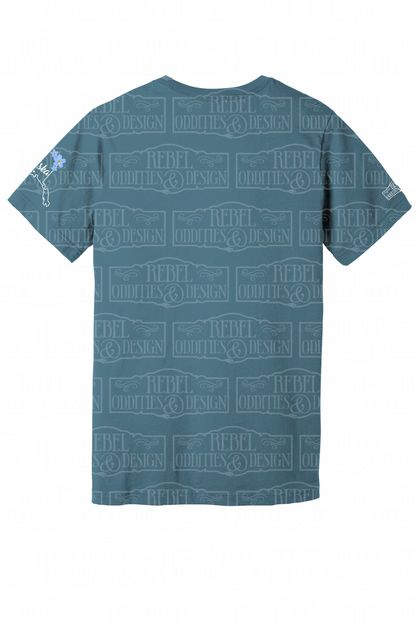 The back of the Steel Blue t-shirt with the shape of Alaska on the left sleeve, a small logo on the right sleeve, and a Forget-Me-Not and Fireweed design on the front against a white background. There is nothing on the back of the shirt.