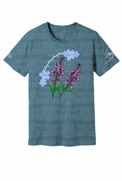 Blue Steel t-shirt with the shape of Alaska on the left sleeve, a small logo on the right sleeve, and a Forget-Me-Not and Fireweed design on the front against a white background.