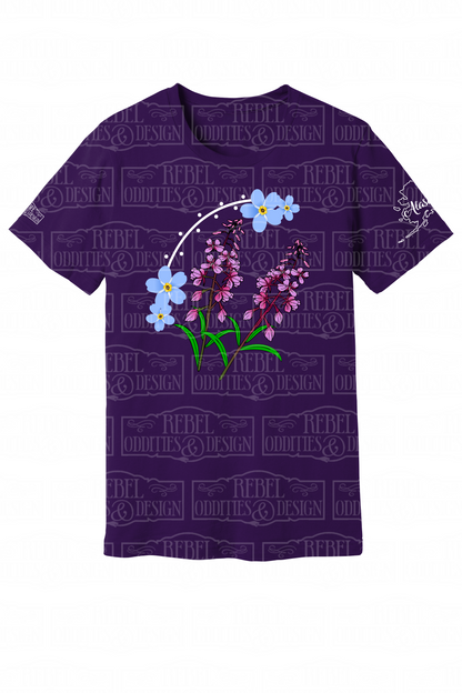 Purple  t-shirt with the shape of Alaska on the left sleeve, a small logo on the right sleeve, and a Forget-Me-Not and Fireweed design on the front against a white background.
