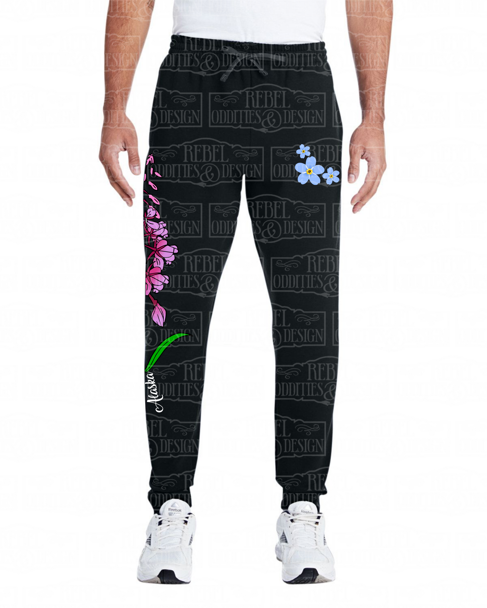 Front view of Black jogger sweatpants with a fireweed design up the side of the right leg, featuring script reading 'Alaska' and three forget-me-nots below the left pocket, along with a small version of the logo on the back of the left leg, all on a white background.